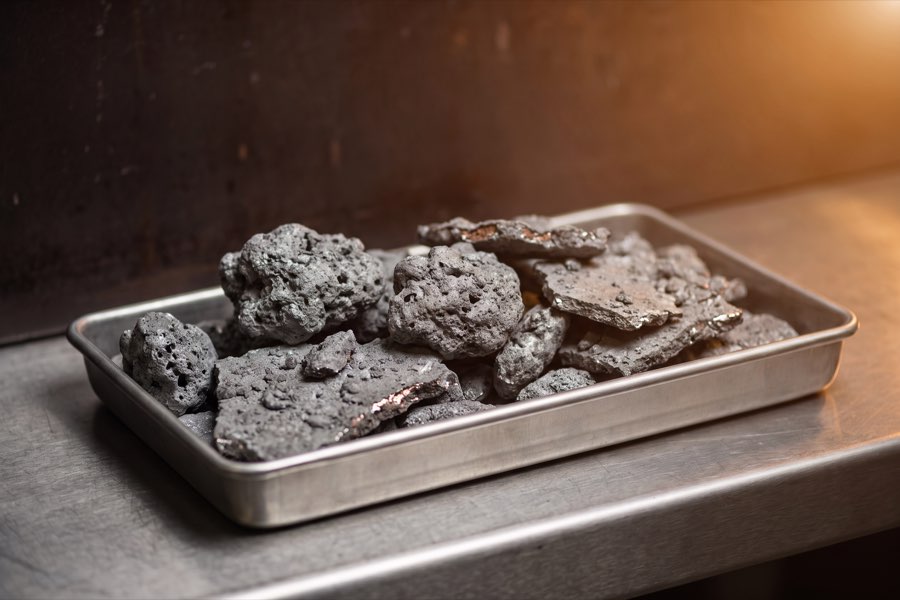 Grey metallic dross and flakes in a stainless steel tray